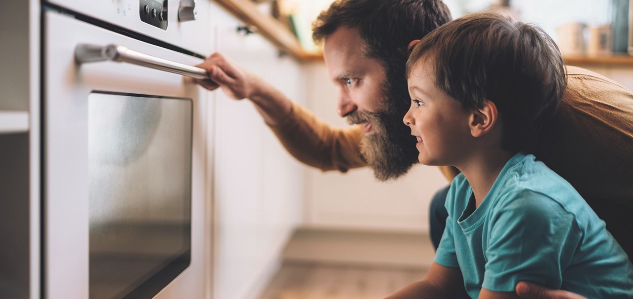Father and son looking at something cooking in the oven