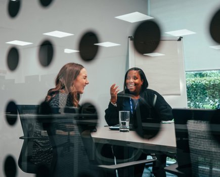 Two women colleagues laughing in a meeting room