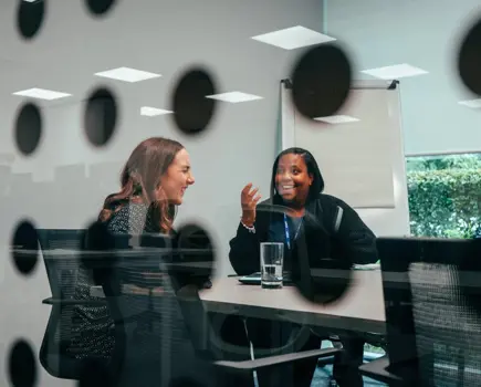 Two women colleagues laughing in a meeting room
